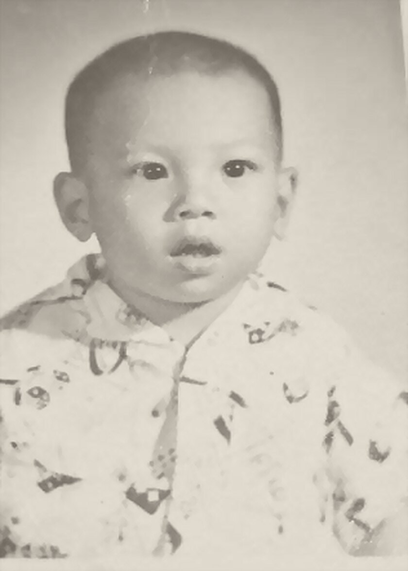 A studio portrait of Tommy as a baby, in a patterned shirt.